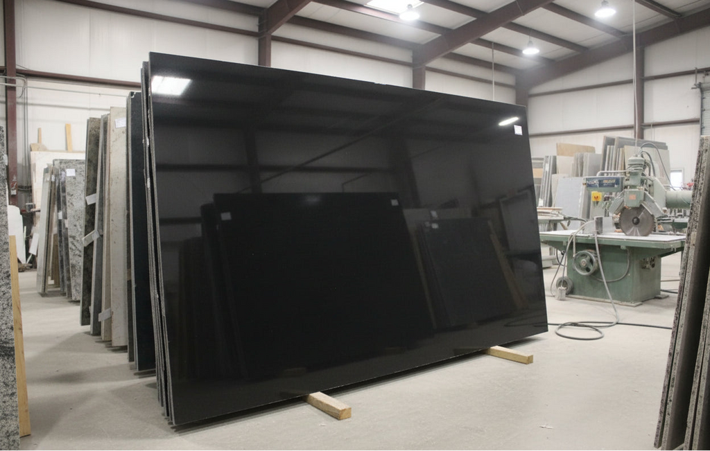 Alt text:
Absolute Black granite slabs in a fabrication workshop, showing a deep polished black surface with strong reflective depth and minimal natural variation.