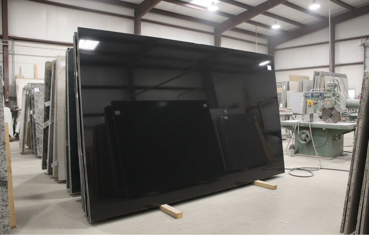 Alt text:
Absolute Black granite slabs in a fabrication workshop, showing a deep polished black surface with strong reflective depth and minimal natural variation.