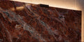 Luxury close-up of polished Rouge des Carpates marble showing warm red tones, natural veining, and concealed halo lighting behind the slab.