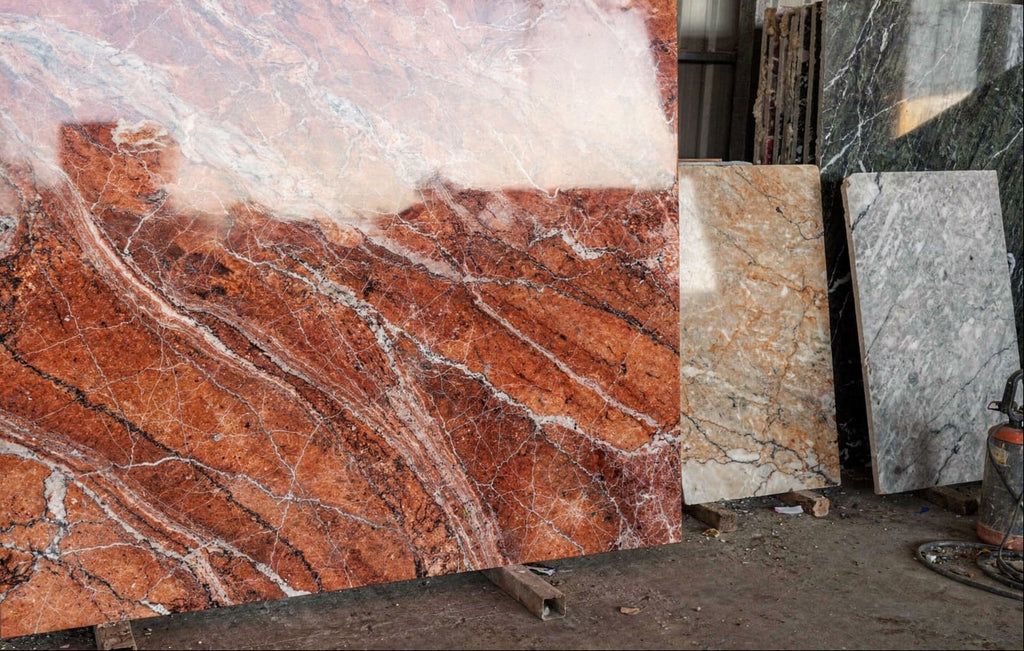 Rouge des Carpates marble slab in a fabrication yard, showing a deep red surface with white veining on a transport stand.